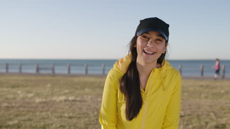 portrait of awkward teenage girl waving laughing cheerful shy looking at camera wearing yellow hoodie seaside park background