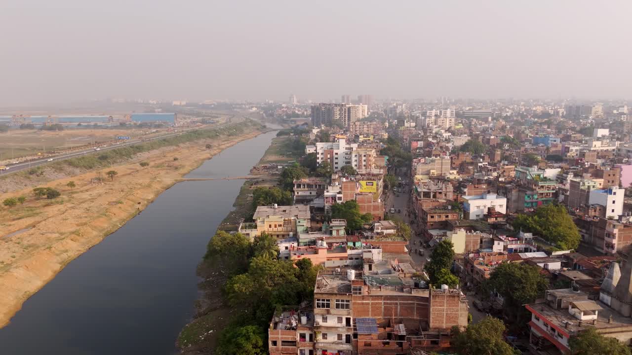 Tier 2 Patna city crowded residential neighbourhood with water channel and JP Ganga Path on left under hazy sky, drone shot