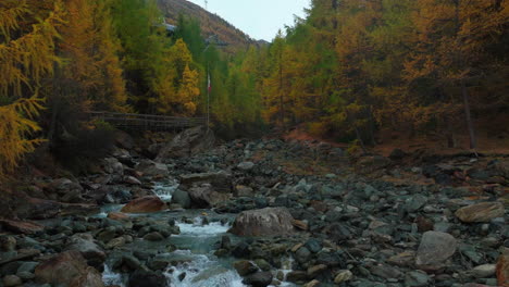 Saas-Fee-Swizerland-glacier-glacial-yellow-autumn-Larch-forest-snowmelt-Feevispa-river-aerial-drone-moody-rainy-fog-mist-cloudy-grey-peaceful-Swiss-Alpine-Alps-valley-mountain-town-chairlift-backwards