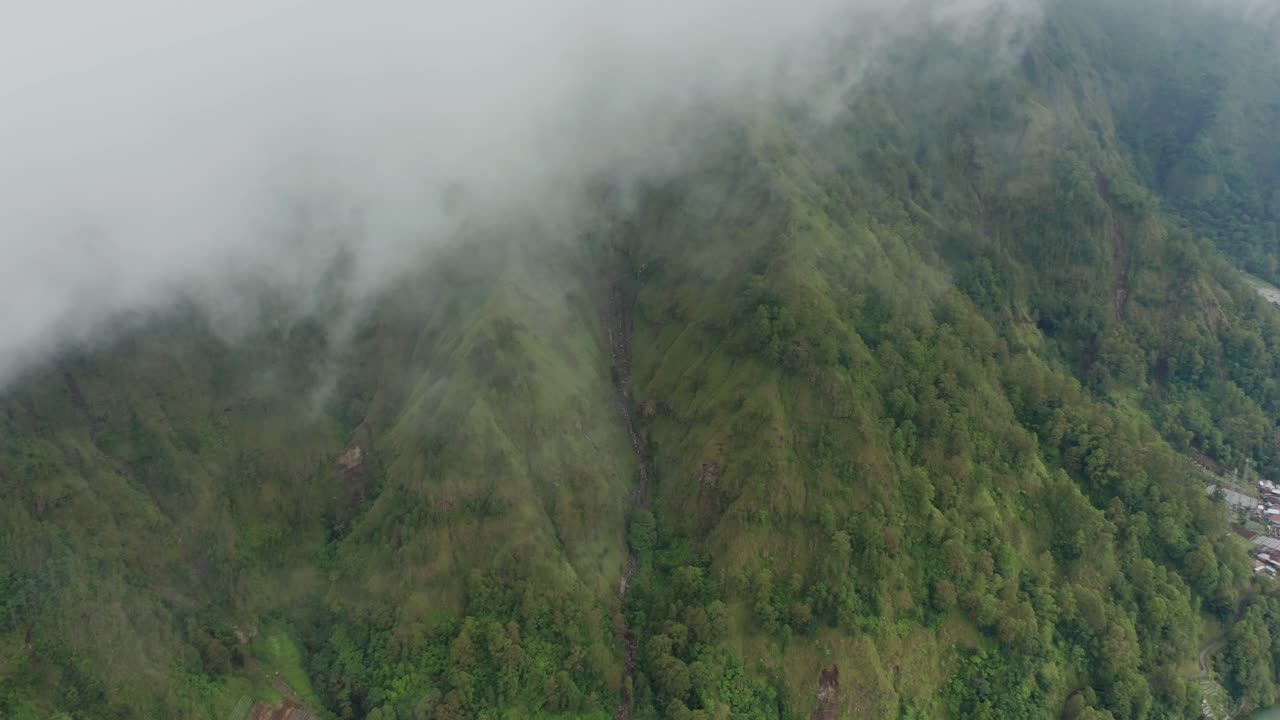 ambiente brumoso con exuberante ladera verde en la caldera del lago batur, aéreo