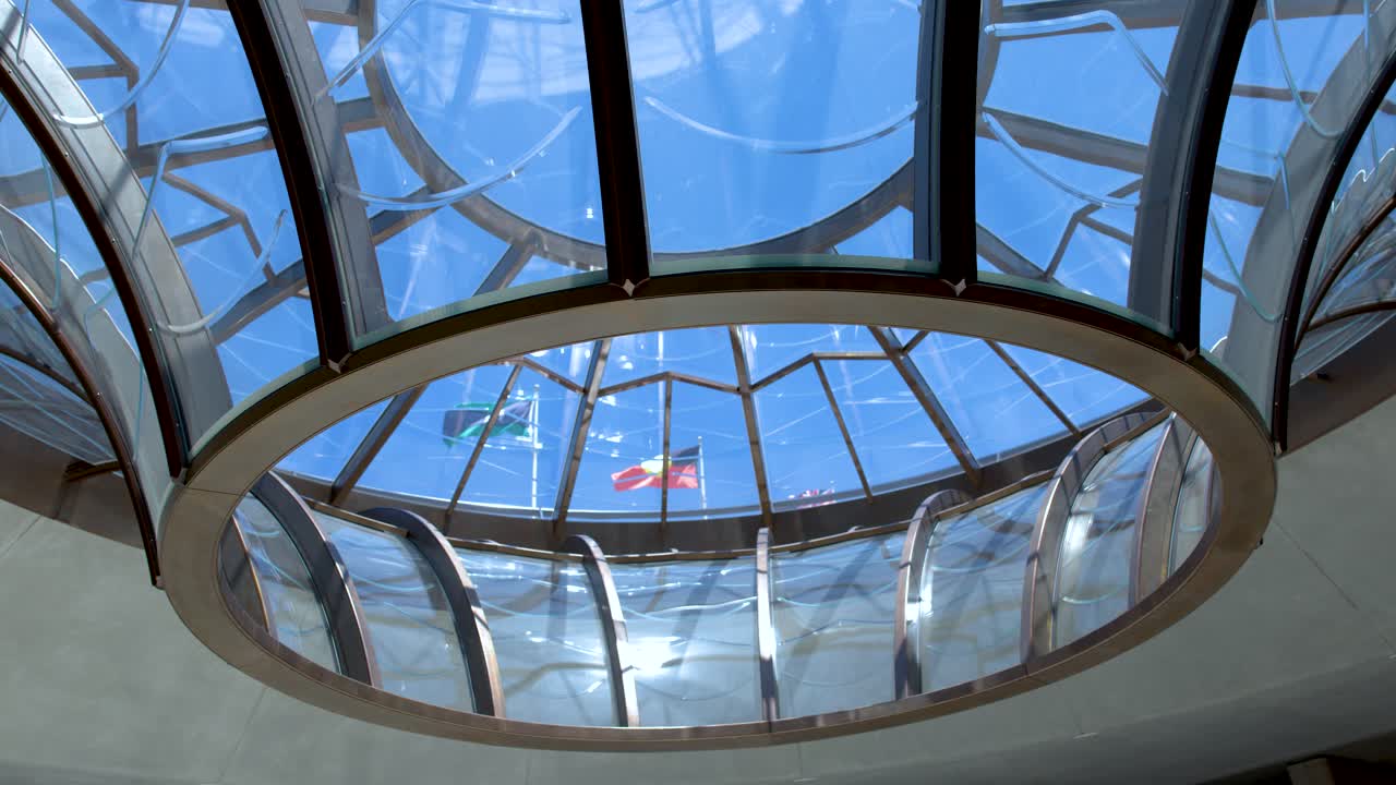 Plano de ángulo bajo de una cúpula de techo de cristal geométrico con banderas visibles a través del cristal