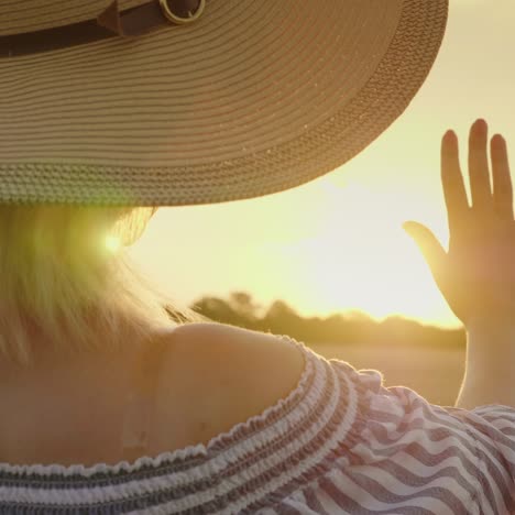 Una-Mujer-Joven-Con-Un-Sombrero-Mira-La-Puesta-De-Sol-Sobre-El-Campo-De-Trigo-1