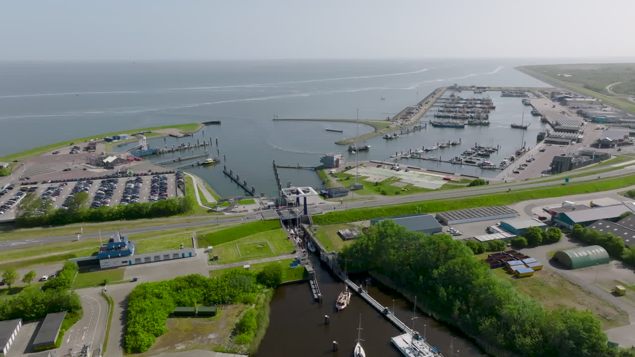 Aerial view of harbour at Lauwersoog in the Netherlands. The video showcases the coastal infrastructure, docked boats, ferry routes and the surrounding green landscape leading into the North Sea