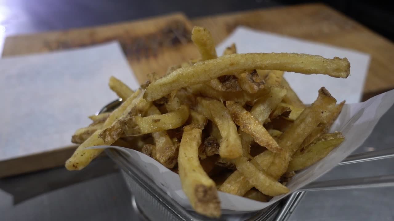 Slow revealing shot of a portion of fries served in a metal basket