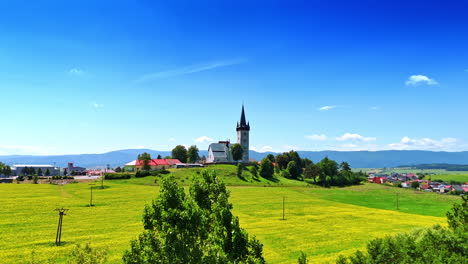 flight over the trees and meadows on sunny day. approaching the little church with a tower. bratislava, slovakia.
