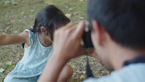 Father-taking-photo-of-cute-little-daughter-playing-with-twig