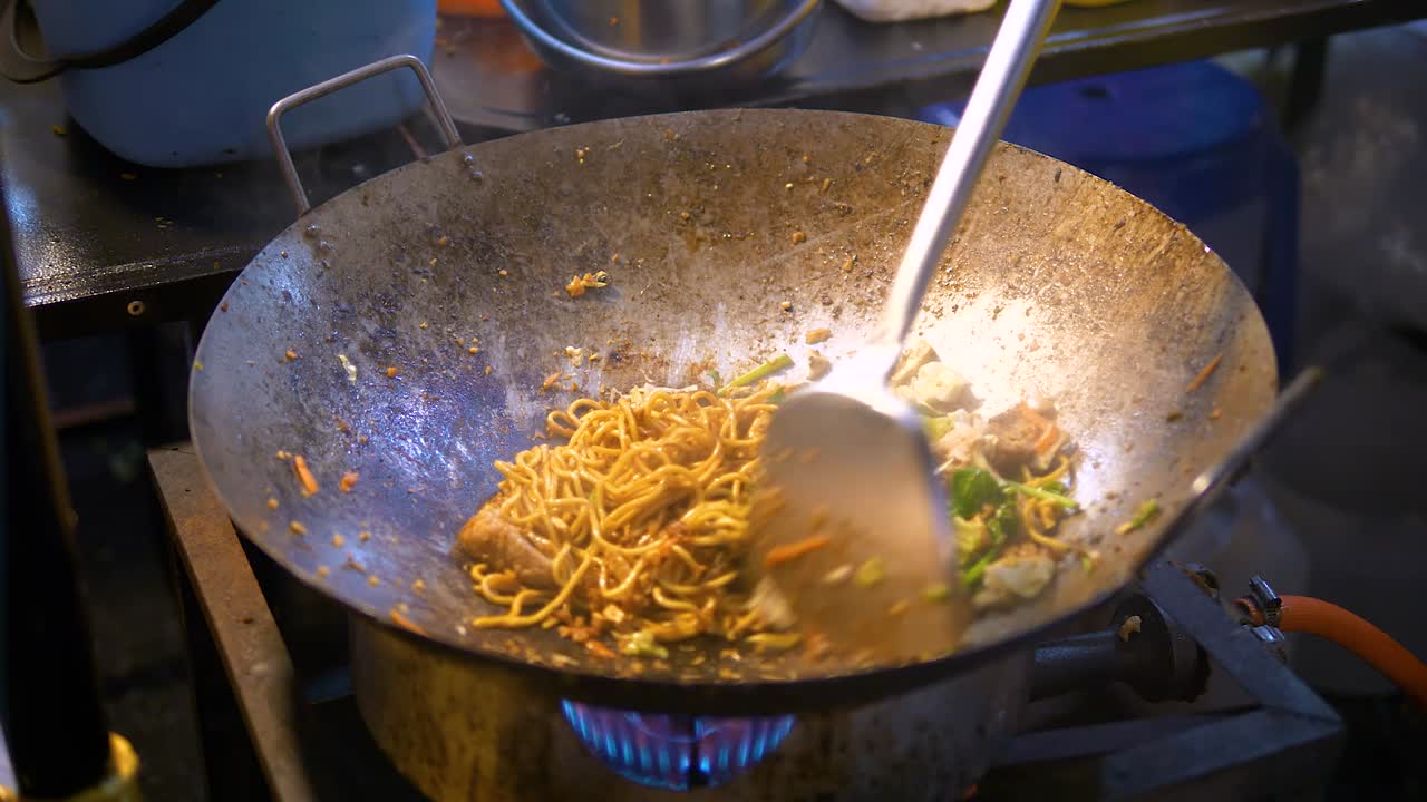 Noodles saltati preparati in un wok per strada.