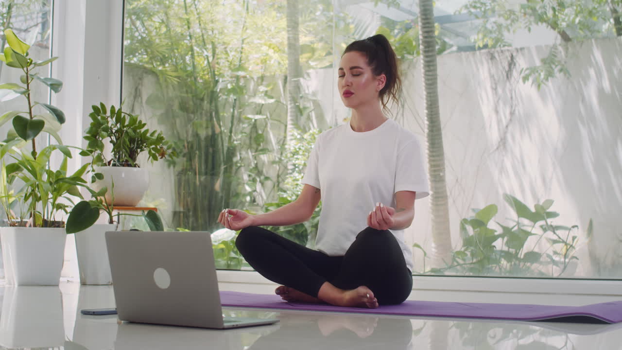 Woman Sitting in Lotus Pose in front of Laptop
