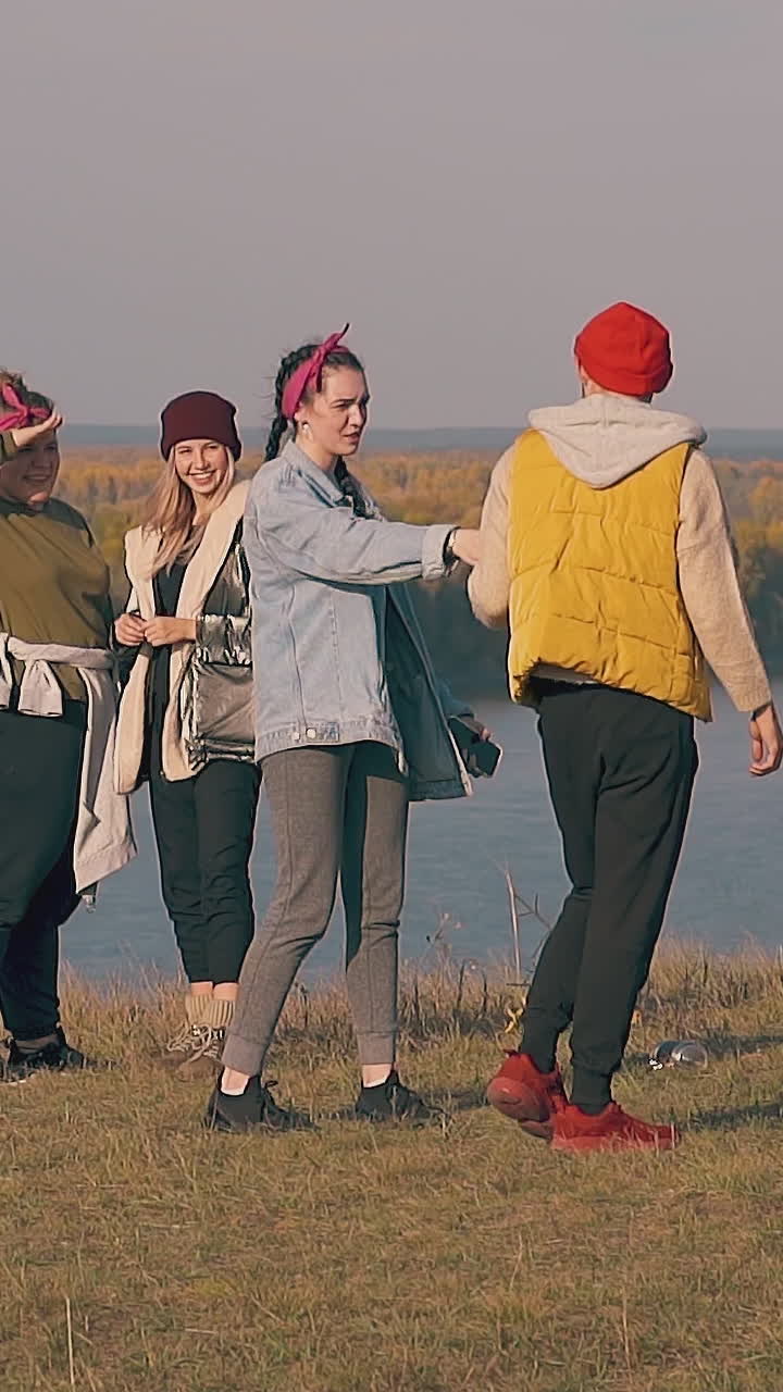 man with hangover walks past smiling girls and lady gives bottle with water against calm river in morning slow motion