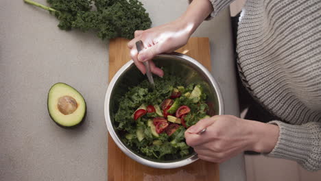 preparación de ensalada de verduras, manos femeninas mezclando ensalada en el tazón para la cena primer plano desde arriba