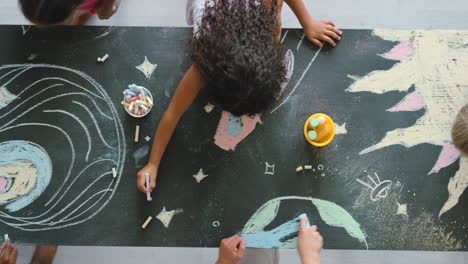 children drawing on a blackboard with chalk