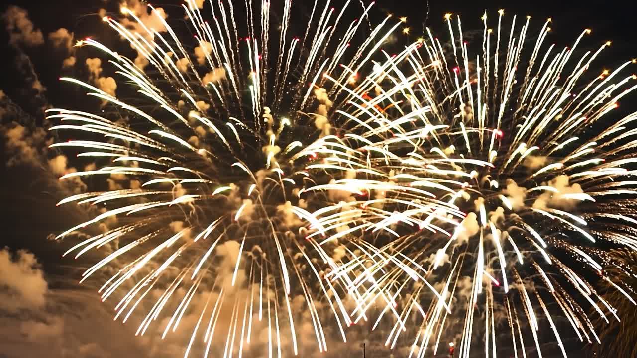 una vibrante exhibición de fuegos artificiales que iluminan el cielo nocturno en una deslumbrante variedad de tonos rojos, verdes y dorados