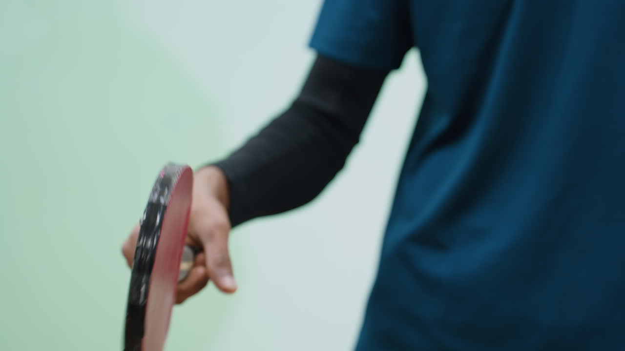 Partial view of tennis player twirling racket in right hand, body slightly turned with focus on paddle and controlled wrist movement, showing concentration