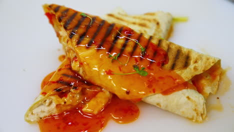 shawarma or doner kebab on white table poured with souce. pita roll is made with tortilla, beef, tomato, onion and lettuce.