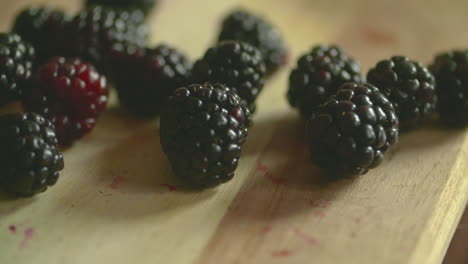 slow motion footage of a bunch of plump, ripe blackberries dropping on to a wood cutting board