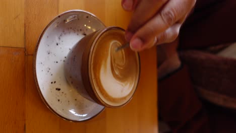 a person stirring a latte art coffee