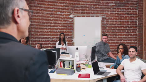 senior businessman talking at meeting of casually dressed business team in open plan office