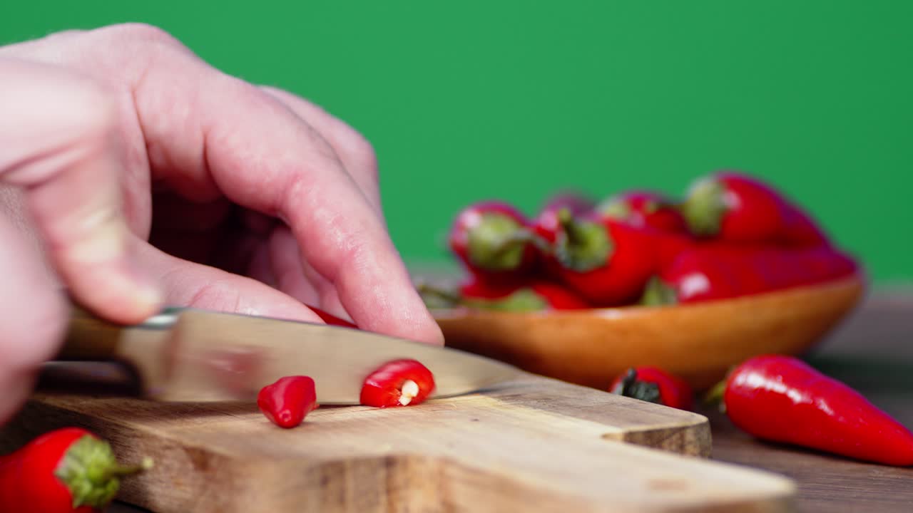 남자 손이 절단판에 은 칠리 고추를 잘라내고 있습니다.