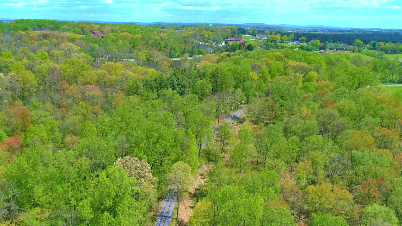 Aerial View of Spring Time Colors of a Forest with a Rail Road Track on a Sunny Day