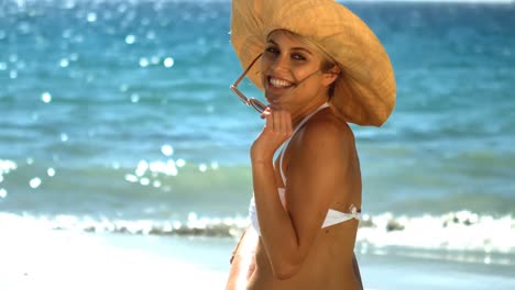 Young-woman-in-bikini-sitting-on-beach