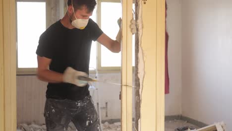 joven cortando el marco de la puerta vigorosamente dentro de un sitio de renovación