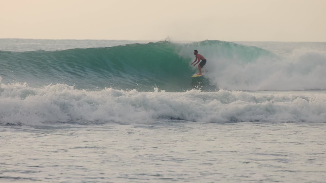 청록색 바다와 멕시코에서 큰 파도를 타고 전문적으로 서핑하는 사람의 슬로우 모션 샷