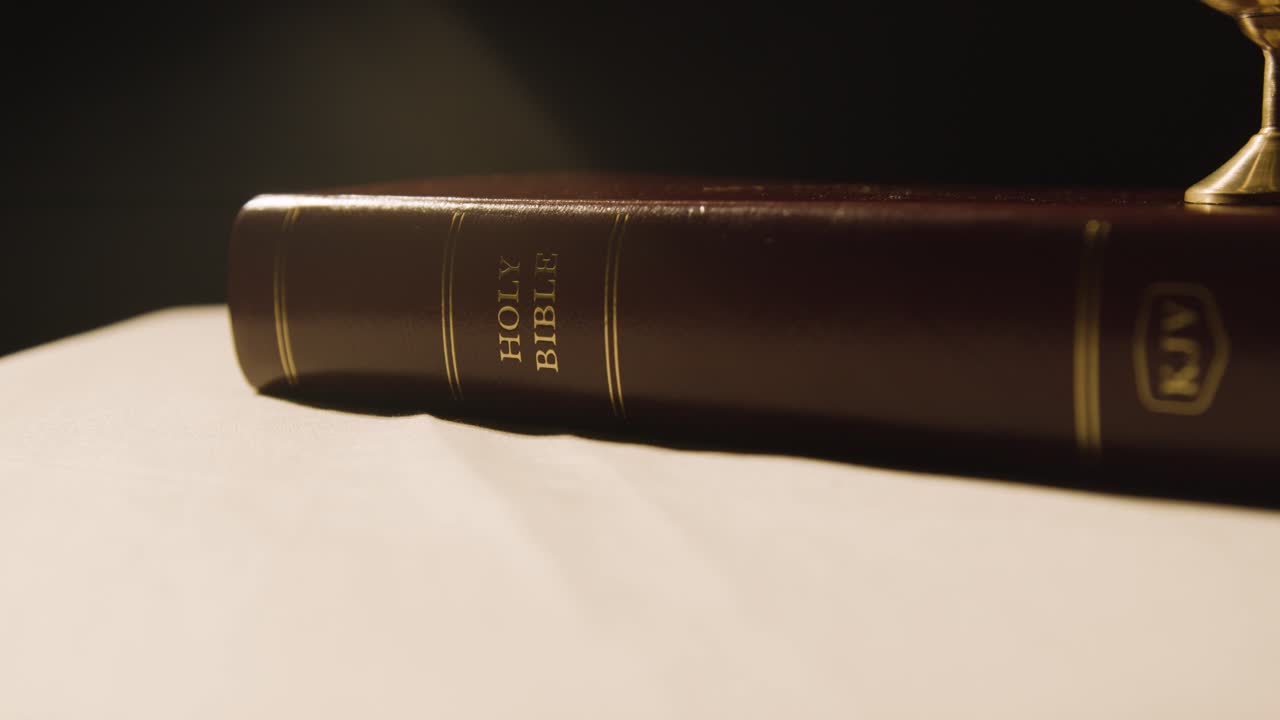 concepto religioso filmado con biblia y cáliz en altar en charco de luz 2