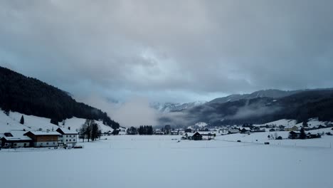 Timelapse-Del-Pueblo-Alpino-Cubierto-De-Nieve-Gosau-En-El-Valle-De-Gosau,-Austria,-Con-Vistas-A-Las-Montañas-Dachstein-De-Los-Alpes-Orientales-En-Una-Mañana-Nublada