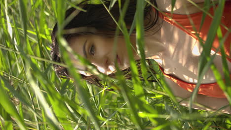 portrait of a young woman in a bikini standing in tall coastal grass