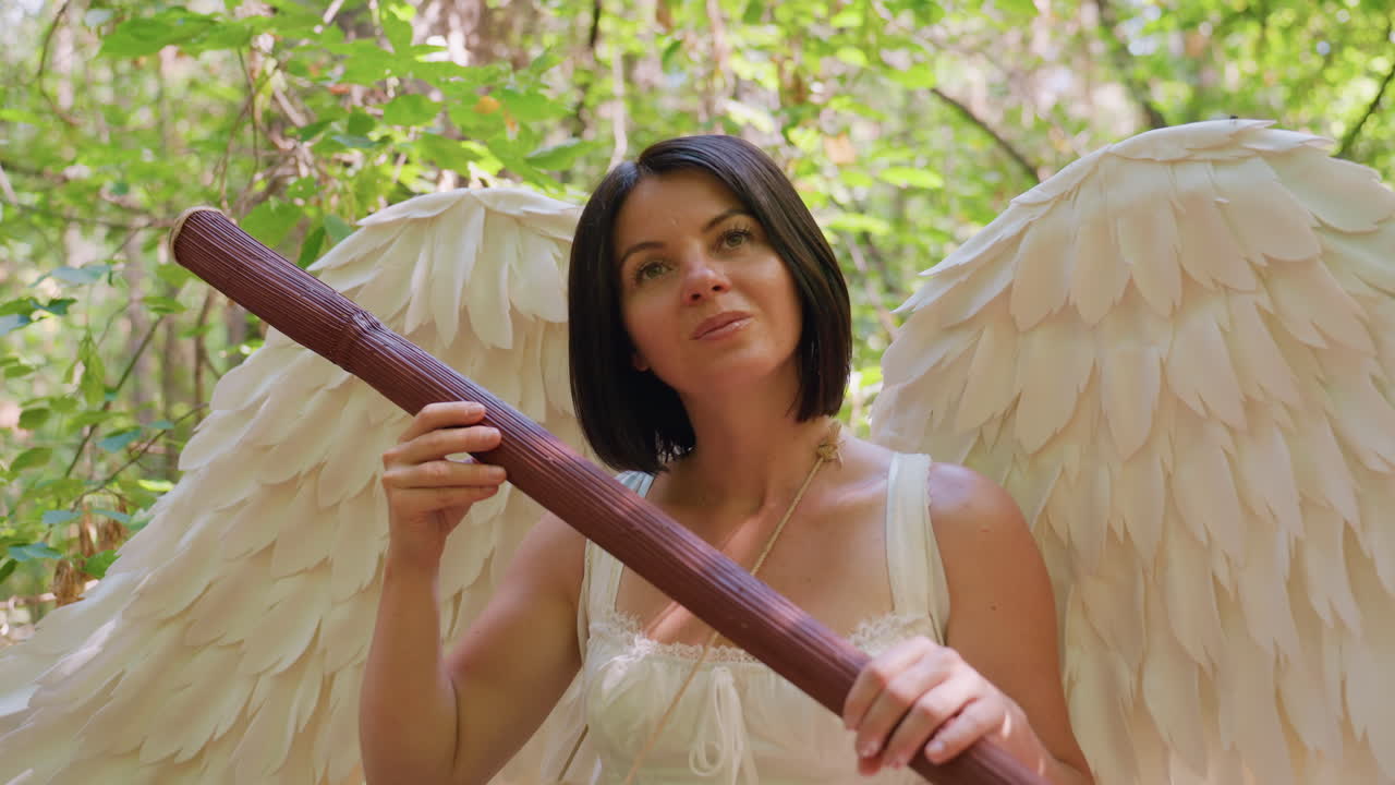 Goddess of love seated in forest holding wooden staff, tapping it like harp with drum around neck, surrounded by glowing sunlight and green leaves, expressing peace