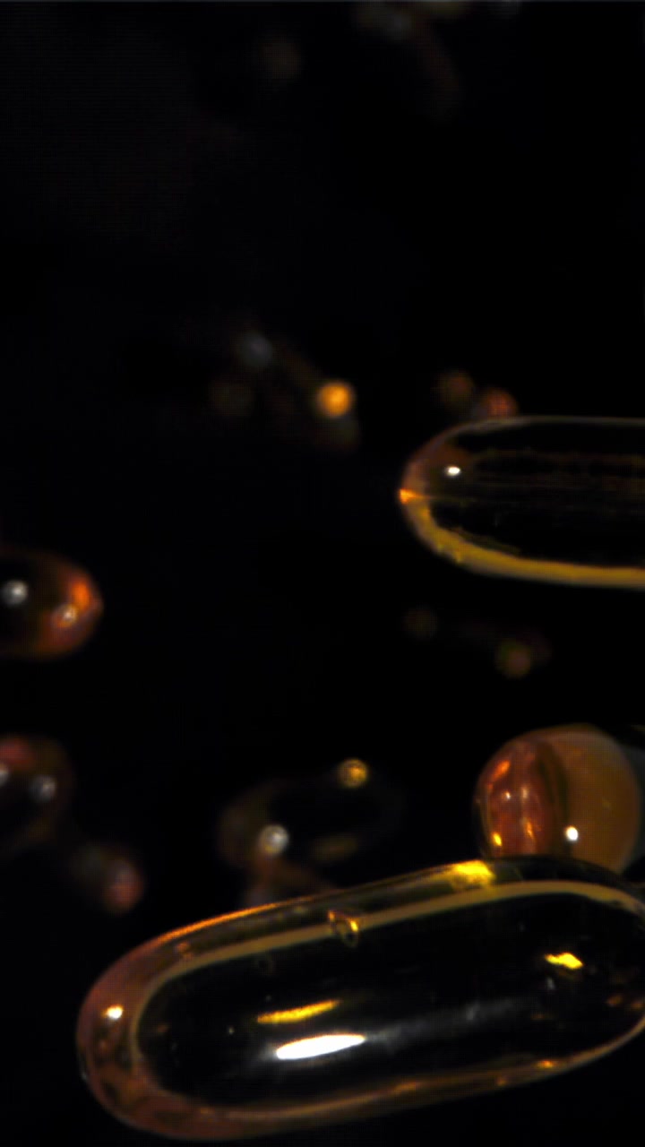 Rallentatore di capsule softgel dorate che galleggiano in liquido scuro