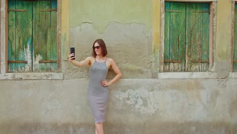 una viajera alegre tomando una selfie cerca de una pared en mal estado