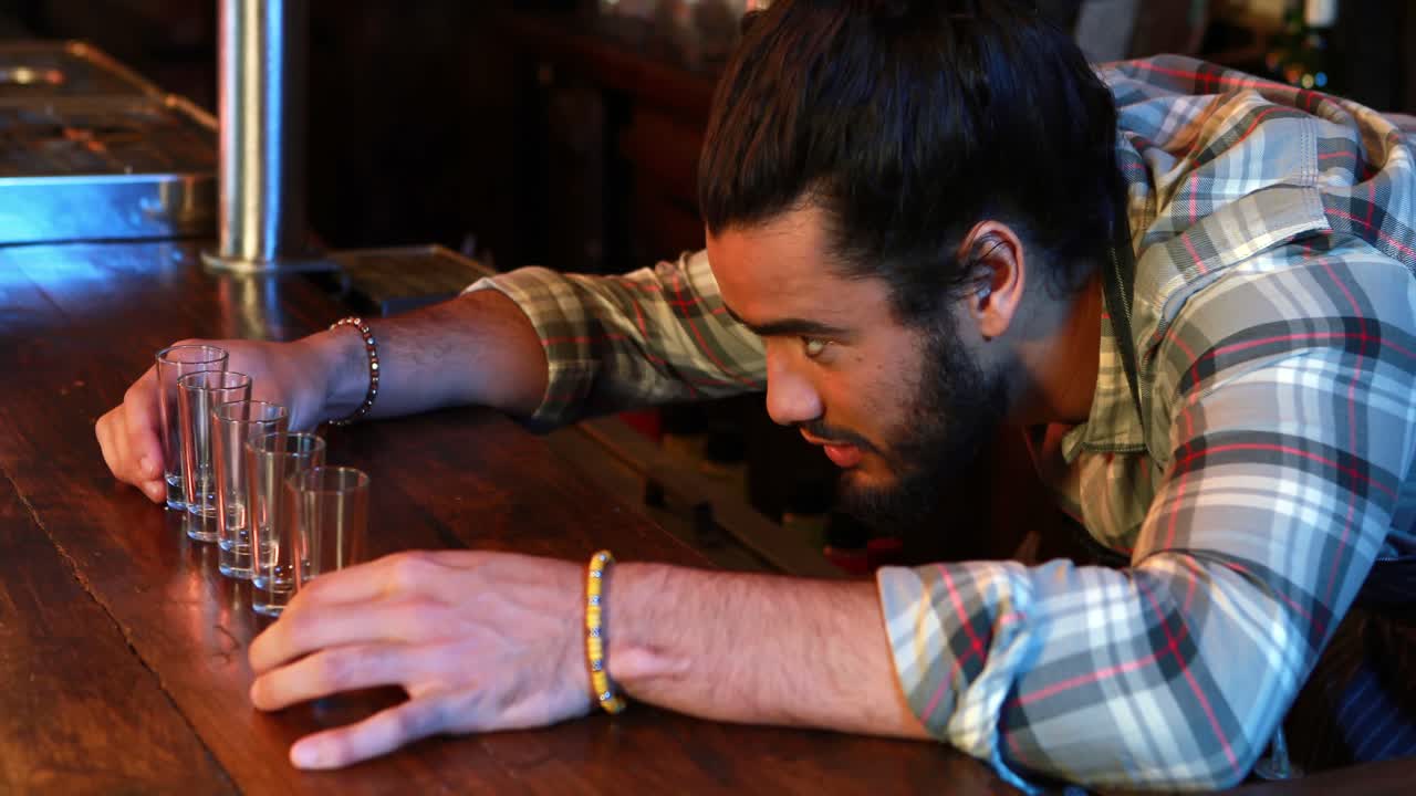barman arreglando vasos de copas en el mostrador de la barra
