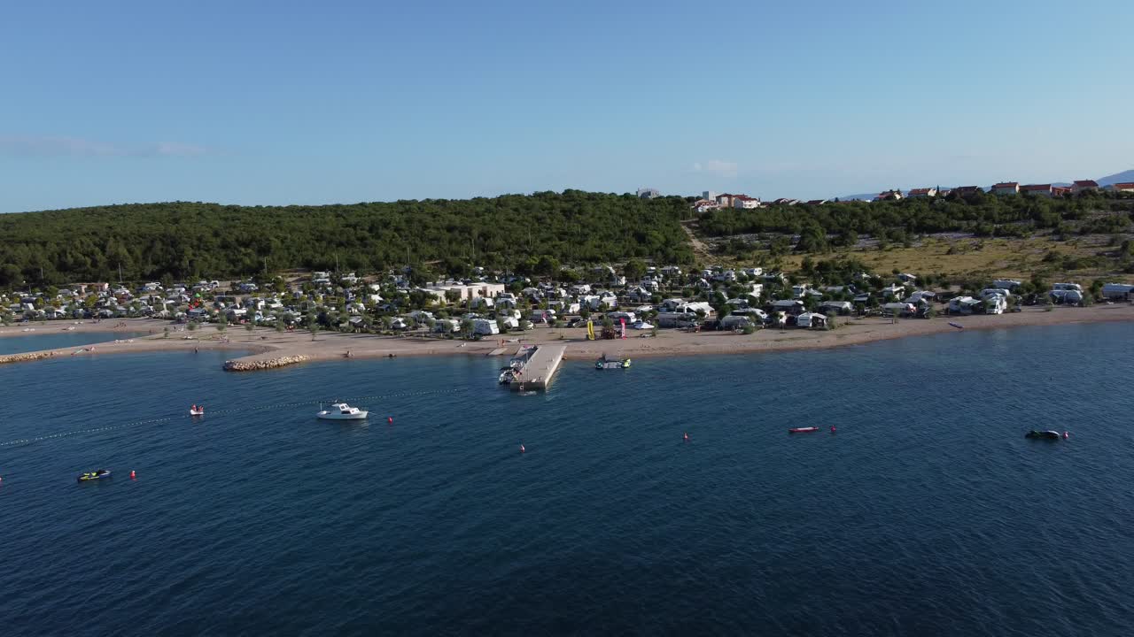 drone acercándose a un camping de 5 estrellas en croacia krk desde la costa con niños divirtiéndose y rv campmobiles en un brillante día de verano