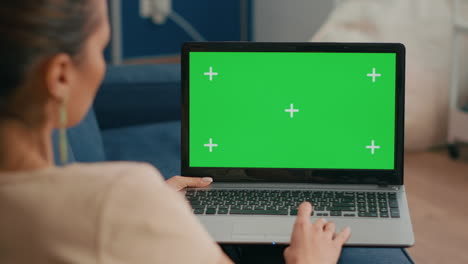 Close-up-of-freelencer-using-laptop-computer-with-mock-up-green-screen-chroma-key-display