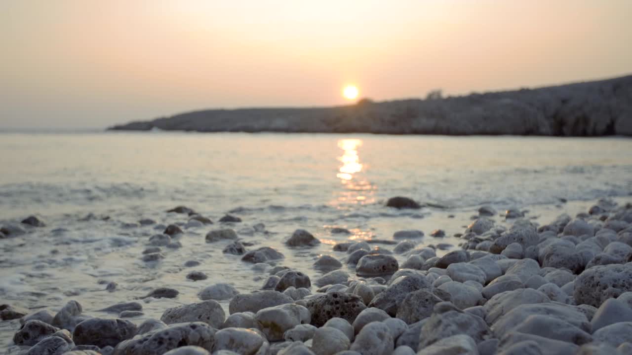 Slow motion shot of waves crashing against white rocks during sunset