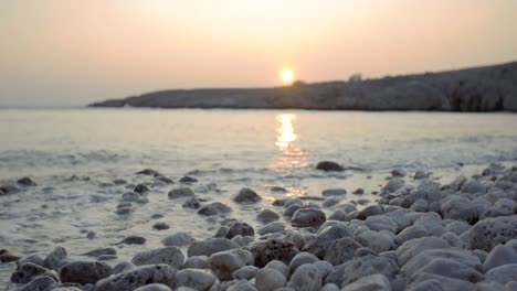 slow motion shot of waves crashing against white rocks during sunset