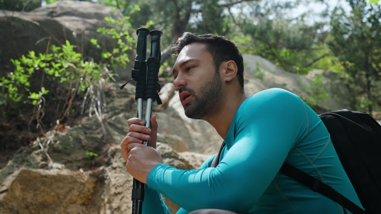 Tired Hiker Sitting on Ground Under Mountain Cliff in a Forest
