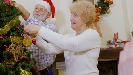 happy old couple decorate christmas tree together