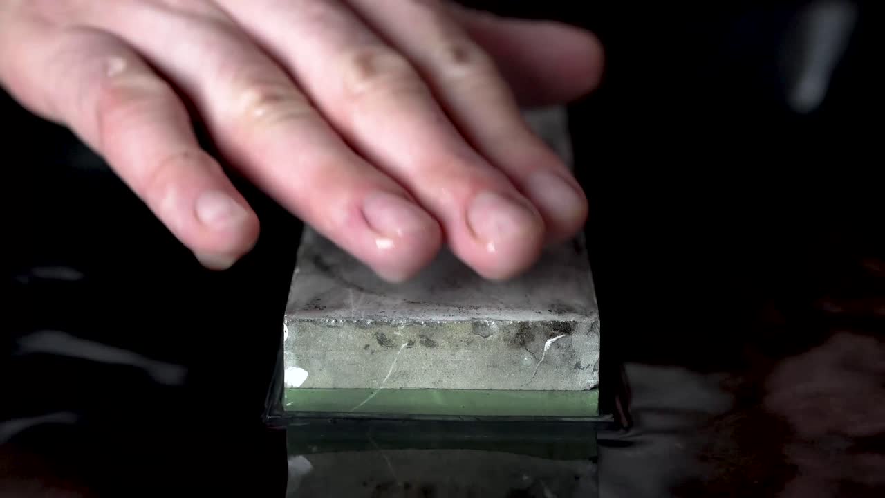 숫돌 표면에 물을 뿌리는 남성 손