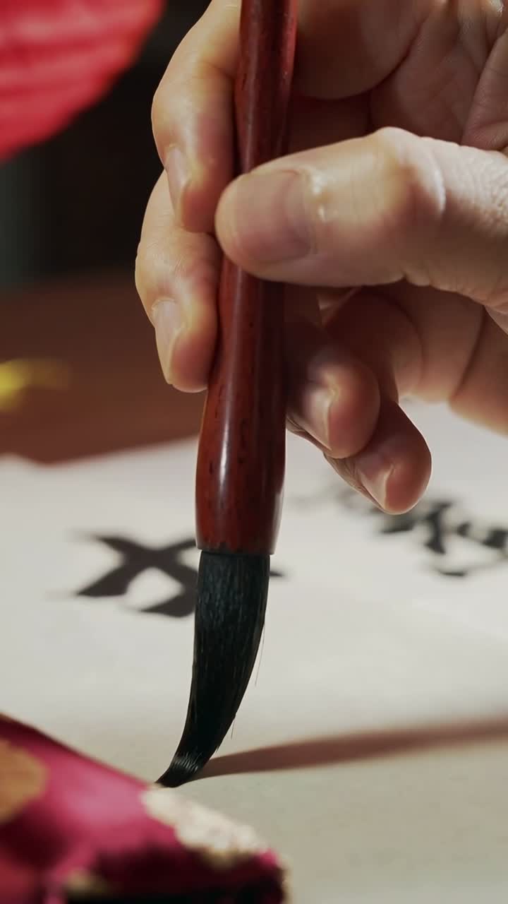 Vertical video: Right hand lowering ink brush drawing ink stroke at table with dish finishing mark