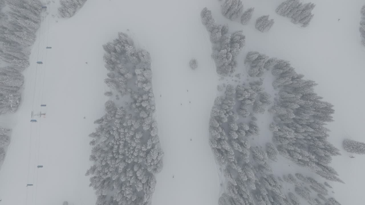 Aerial top down view of skiers skiing down Cooper Mountain in Colorado, USA. Snowstorm.