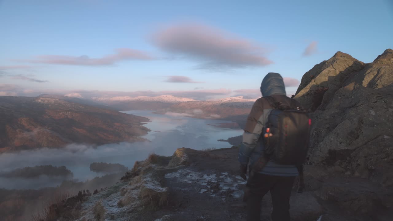 una foto de un excursionista caminando hacia el borde con vistas al lago katrina desde ben a'an