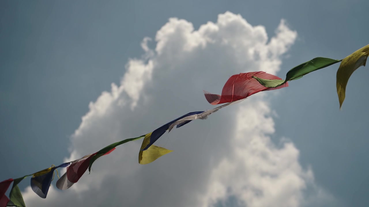 Bandiere di preghiera tibetane e cielo azzurro in Nepal. Bandiere di preghiera tibetane colorate sventolano al vento presso un tempio buddista a Kathmandu, Nepal. Primo piano in una giornata luminosa e soleggiata, sotto il sole.