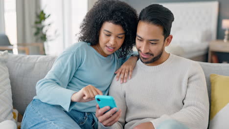 happy multiracial couple on couch with phone