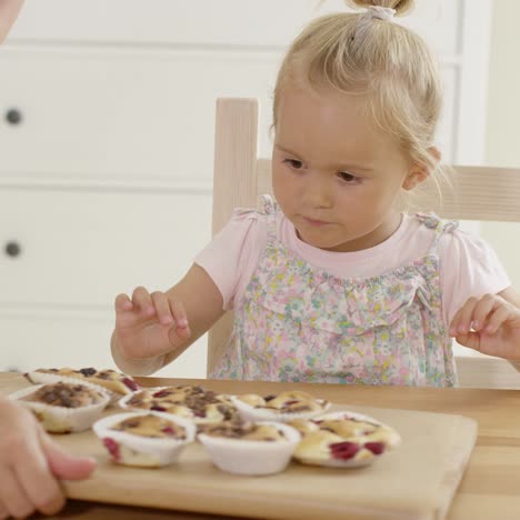 mujer colocando una bandeja de muffins frente a un niño