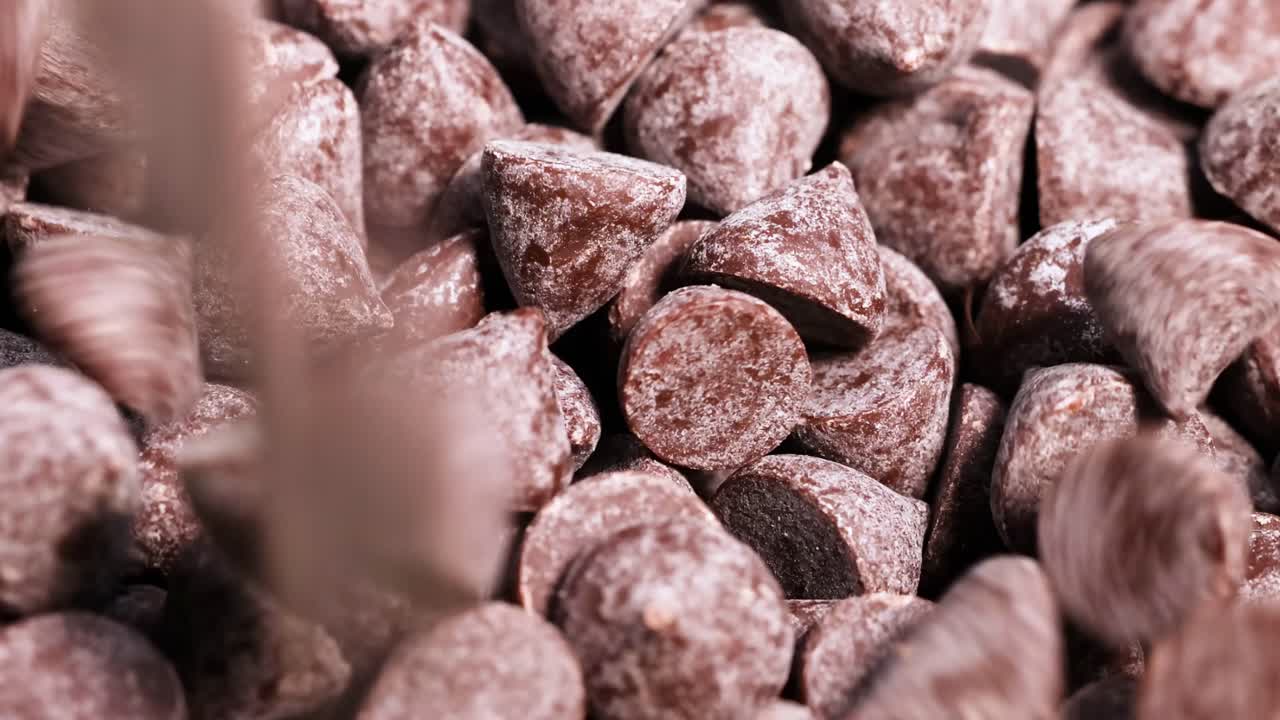 A detailed view of chocolate chips piled together, showcasing texture and form in a close-up perspective.