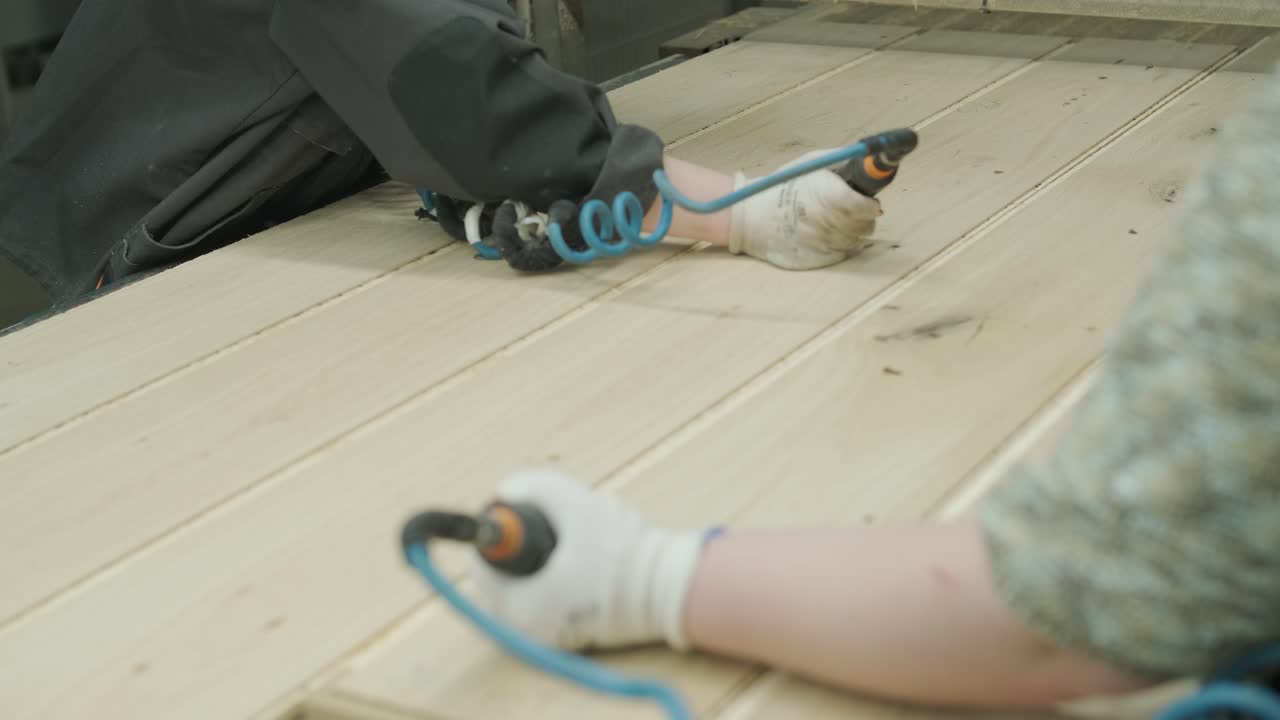 Workers Assembling Wooden Planks with Pneumatic Tools in a Factory
