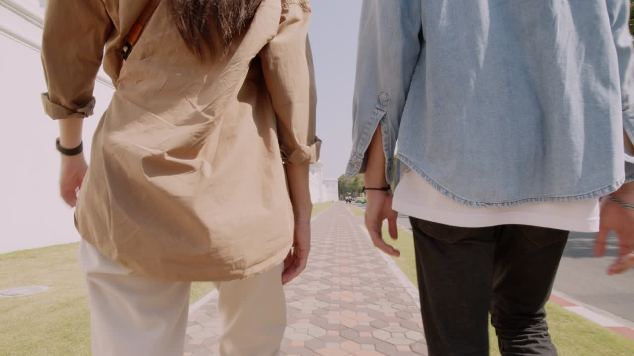 Asian couple tourist walking beside Wat Phra Kaew temple.