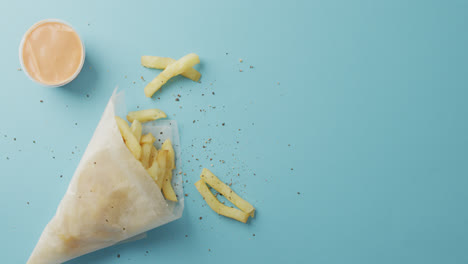 video de chips envueltos en papel, sal y pimienta y salpicaduras, con espacio de copia en fondo azul
